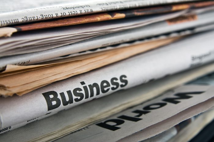 A stack of newspaper sections that includes the Business section.